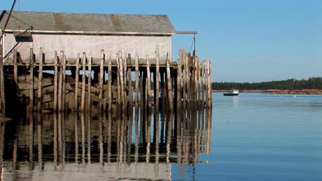 at a lobster village in stonington maine a building is held over water by wooden pillars and rocks