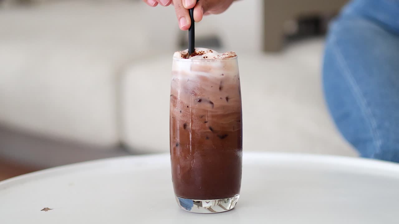 Latte al cioccolato che viene versato in un bicchiere trasparente.