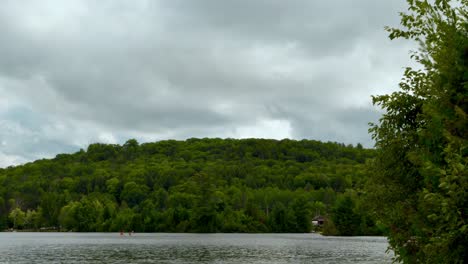 TIMELAPSE---Storm-Clouds-Brewing-Menacingly-Over-Forested-Hill-and-Lake