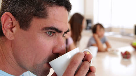 father drinking coffee while his family are eating breakfast