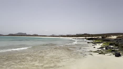 santa monica beach in boa vista, cape verde, showcasing turquoise waters and distant view of an abandoned hotel. highlights the serene coastal landscape and untouched beauty of the island