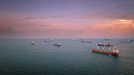 Bulk-cargo-container-ships-anchored-near-Singapore-Port-at-sunset,-aerial-view