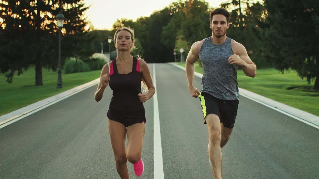 Sport people running in park together. Young couple jogging at outdoor workout