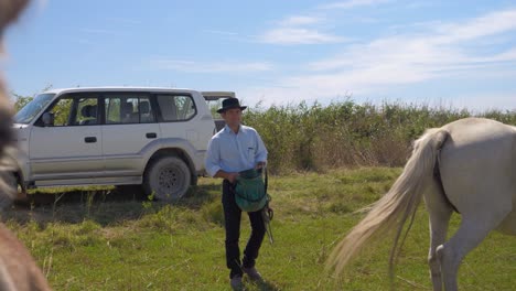 cowboy walking out of the car to show the horses he has food for them