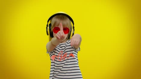 playful funny little kid child girl listening music via headphones, dancing disco fooling having fun