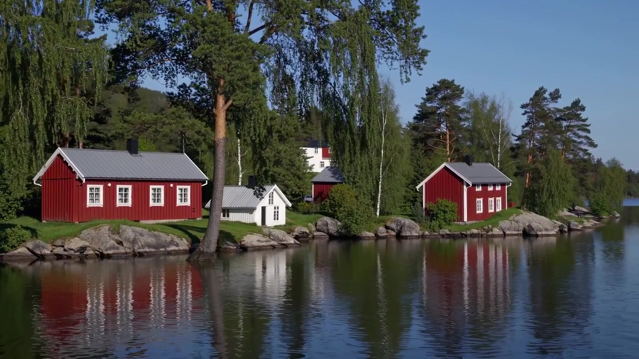 Tradisjonelle røde trehytter ved en rolig innsjø i Sverige