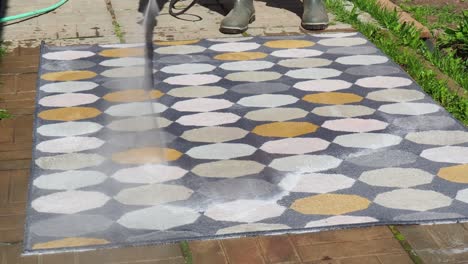man washing carpet with pressure washer outdoors