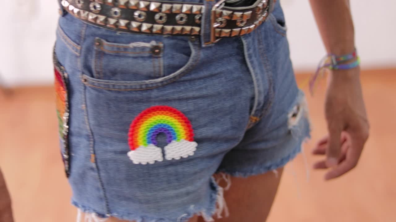 Wearing jeans shorts with studded belt and rainbow LGBTQ accessories