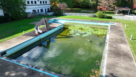 Piscina-Descuidada-Con-Crecimiento-De-Algas-Y-Tobogán.