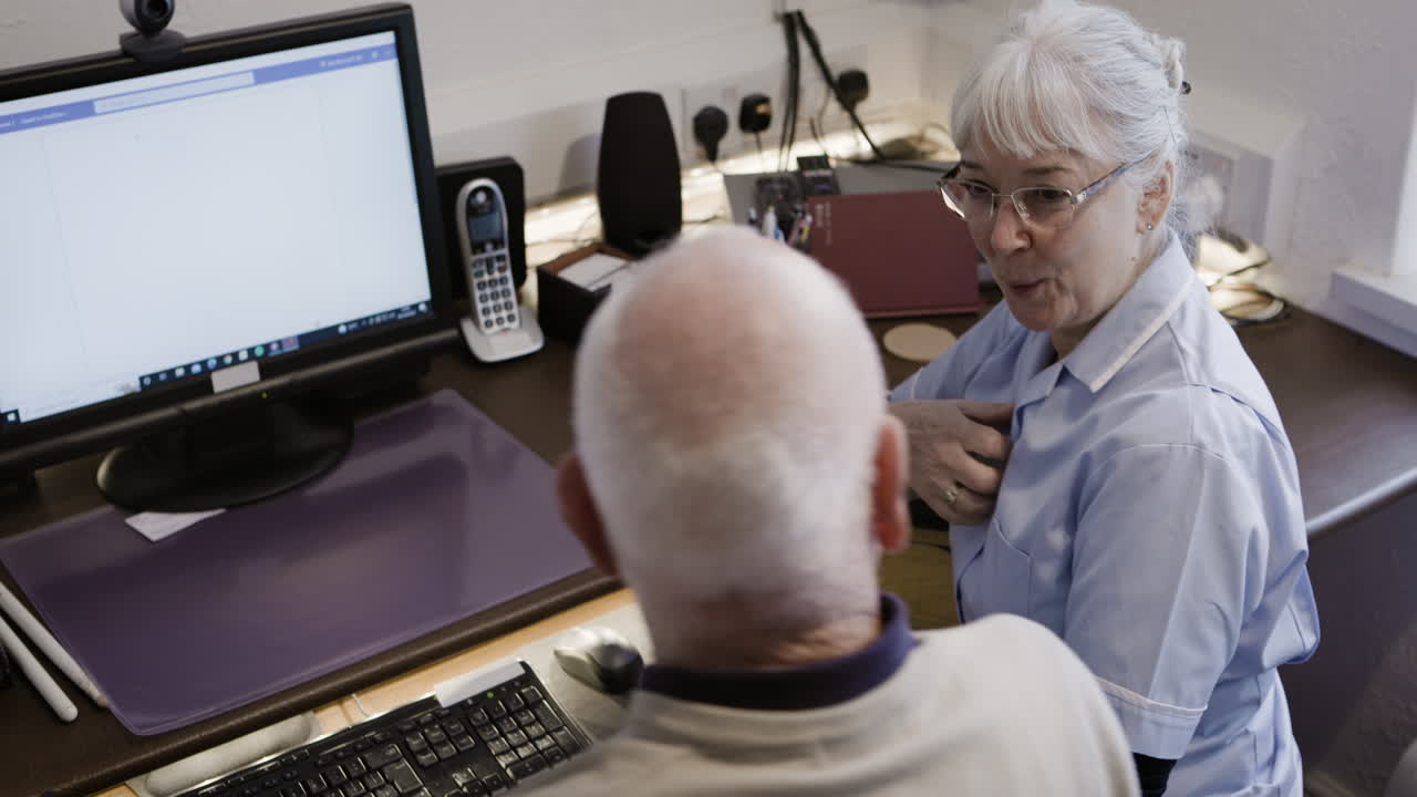 Nurse assisting elderly patient with computer