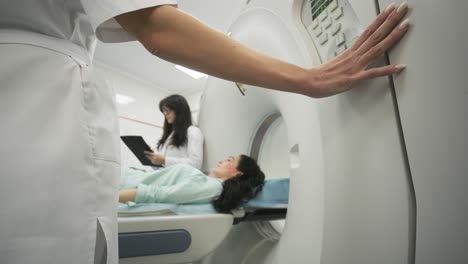 female patient is undergoing ct or mri scan under supervision of two qualified radiologists in modern medical clinic. patient lying on a ct or mri scan table, leaves the machine