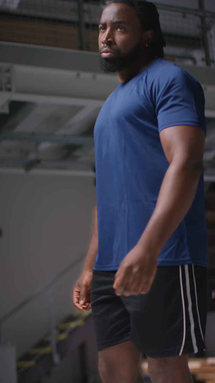 video vertical de un atleta masculino decidido entrenando en el gimnasio de pie y calentándose en el vestuario con expresión enfocada