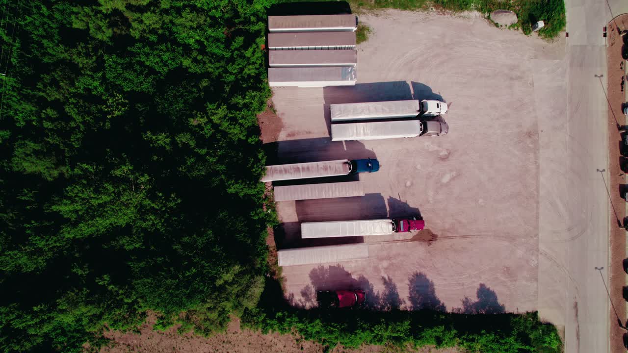 아메리카의 물류 인프라를 보여주는 숲의 가장자리에 주차된 건조한 밴과 냉장 트레일러를 가진 반 트럭의 위에서 아래로 볼 수 있습니다.
