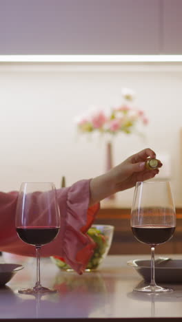 long haired woman criminal pours venomous product into cloying lover wine looking aside during romantic date in kitchen at home slow motion