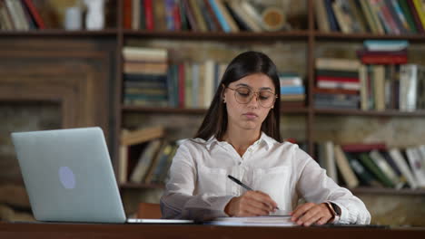 una mujer joven estudiando en una biblioteca.