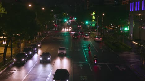 street traffic at night in taipei with cars and scooters with their headlights on – wide shot