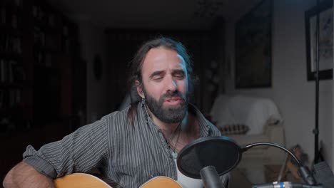 man singing and playing acoustic guitar at home