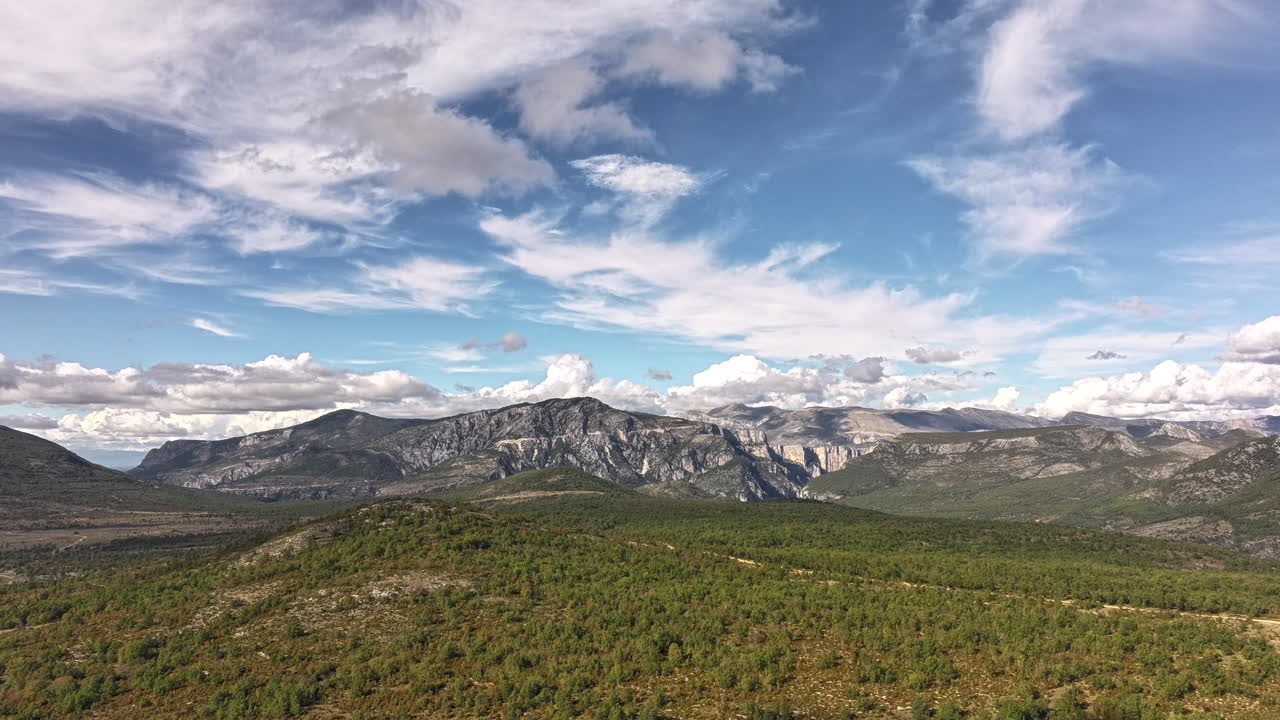 Drone hyperlapse pulling back over Verdon Gorge, France. Dramatic cliffs, canyon, forest and moving clouds create a breathtaking cinematic travel and nature landscape