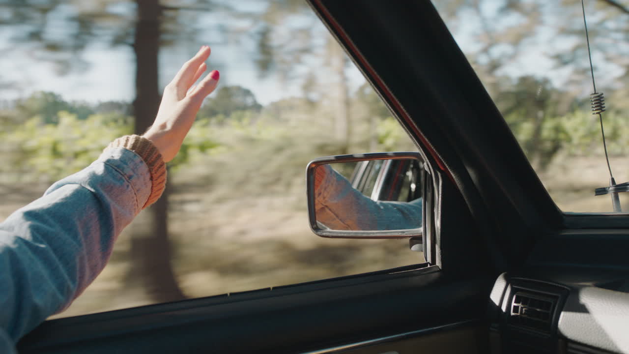 mujer con la mano en la ventana del coche sintiendo el viento soplando a través de los dedos conduciendo en el campo viajando en vacaciones de verano viaje por carretera disfrutando de la libertad en la carretera