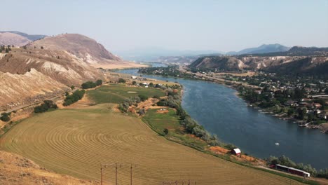 Hermosa-Vista-Aérea-Del-Campo-Y-La-Carretera-Rodeada-Por-Un-Lago-Y-Montañas