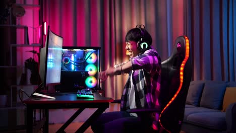 excited asian teen boy gamer celebrates victory and dancing while playing video game on computer