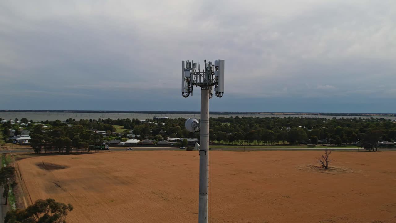 círculo descendente aéreo alrededor de una torre de teléfono móvil con el lago mulwala en el fondo