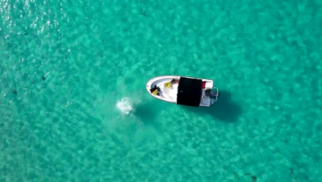 vista aérea de una mujer saltando de un bote a un agua azul tropical