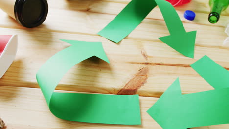 cierre de la basura y el símbolo de reciclaje de flechas de papel verde sobre fondo de madera