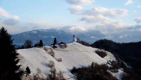 Vista-De-La-Iglesia-Jamnik-En-Un-Paisaje-Invernal-Con-Un-Colorido-Amanecer-En-Kranj,-Eslovenia