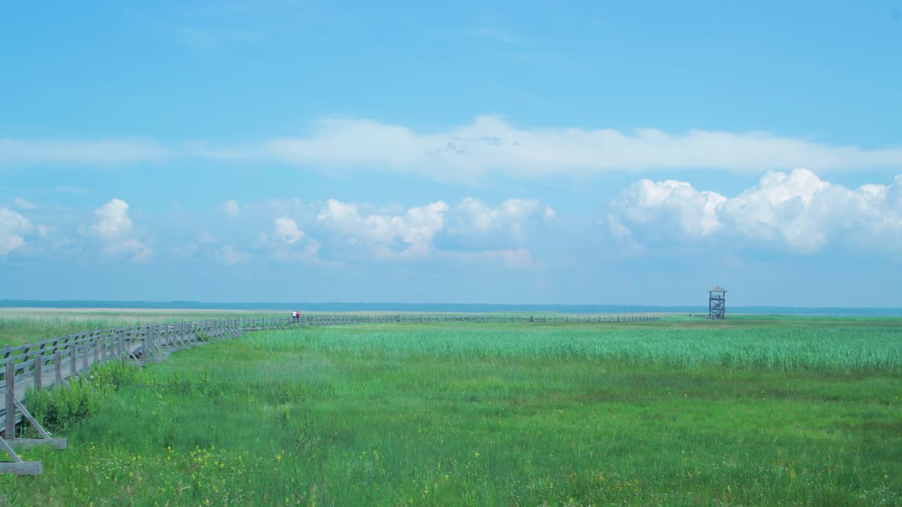 화창한 날, 리에파자 호수 조류 관찰 탑을 향해 걸어가는 사람들과 함께 아름다운 하얀색 빠르게 움직이는 구름과 하늘