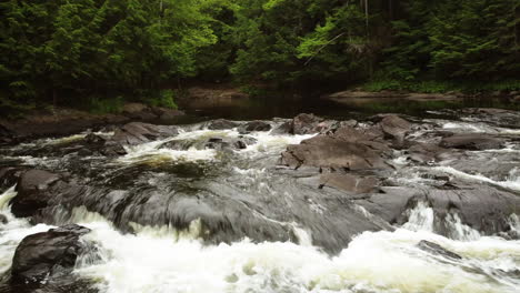 slowly passing close over the top of water cascading, oxtongue falls, algonquin park, aerial track