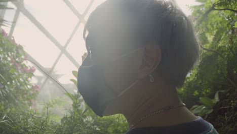 traveler wearing facemask looking on scenic view landscape at the cloud forest - tourist attraction in singapore - backview, orbit