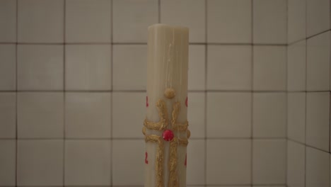 Intricate-Paschal-candle-with-gold-detailing-against-tiled-background,-symbolizing-faith