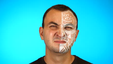 man with painted face is bothered by a bad smell then he gets angry on blue background