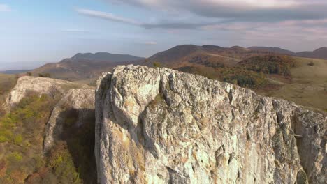 Aerial-panning-shot-of-big-high-rock-on-the-edge-of-a-mountain-1