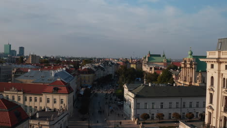 Forwards-fly-above-Krakowskie-Przedmiescie.-Prestigious-street-surrounded-with-palaces-and-manor-houses.-Pedestrians-walking-on-street-in-afternoon.-Warsaw,-Poland