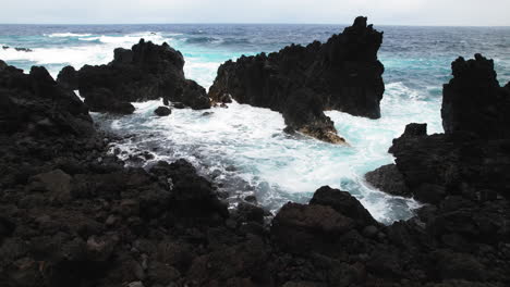 Drone-shot-over-young-couple-watching-powerful-waves-crash-over-lava-rock-in-Hawaii