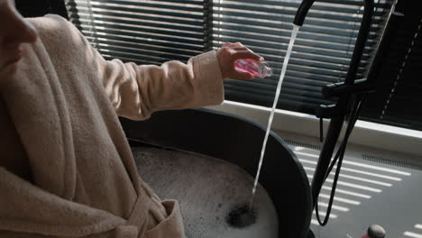 Woman pouring liquid into a bath