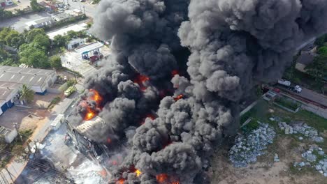 almacén en llamas y enorme columna de humo en la zona industrial de la ciudad