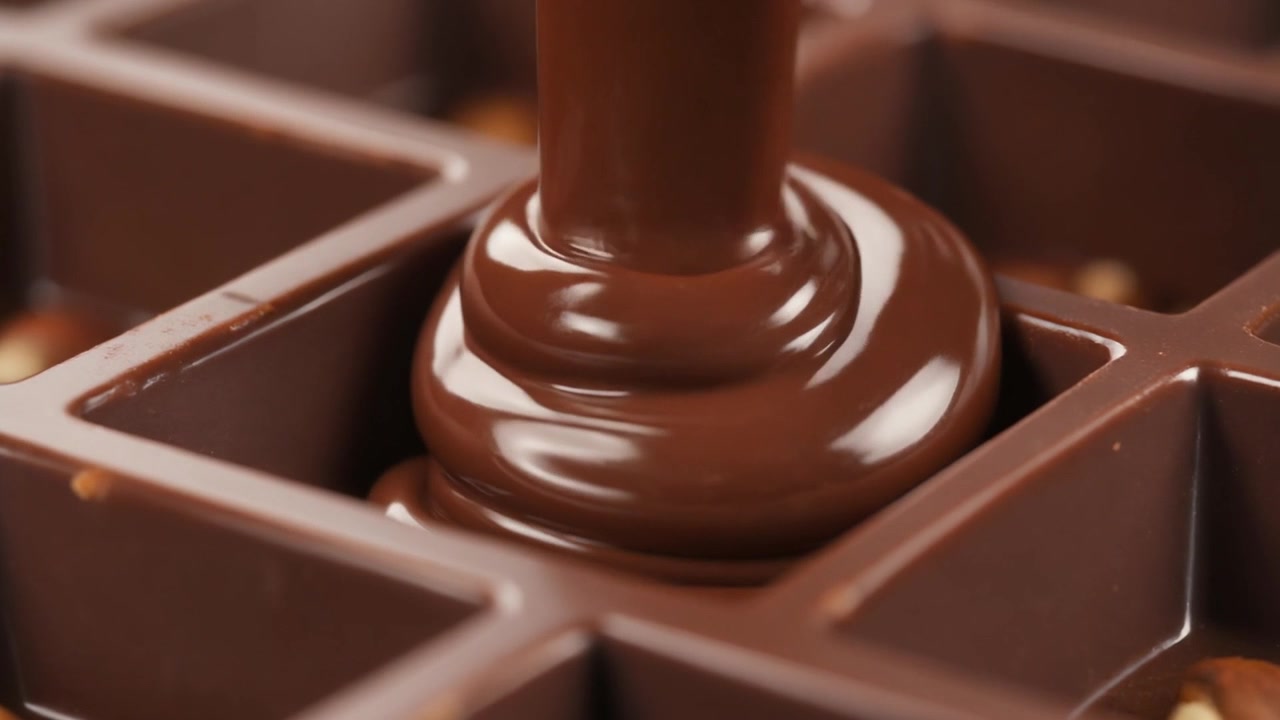 Cioccolato liquido versato in uno stampo con nocciole