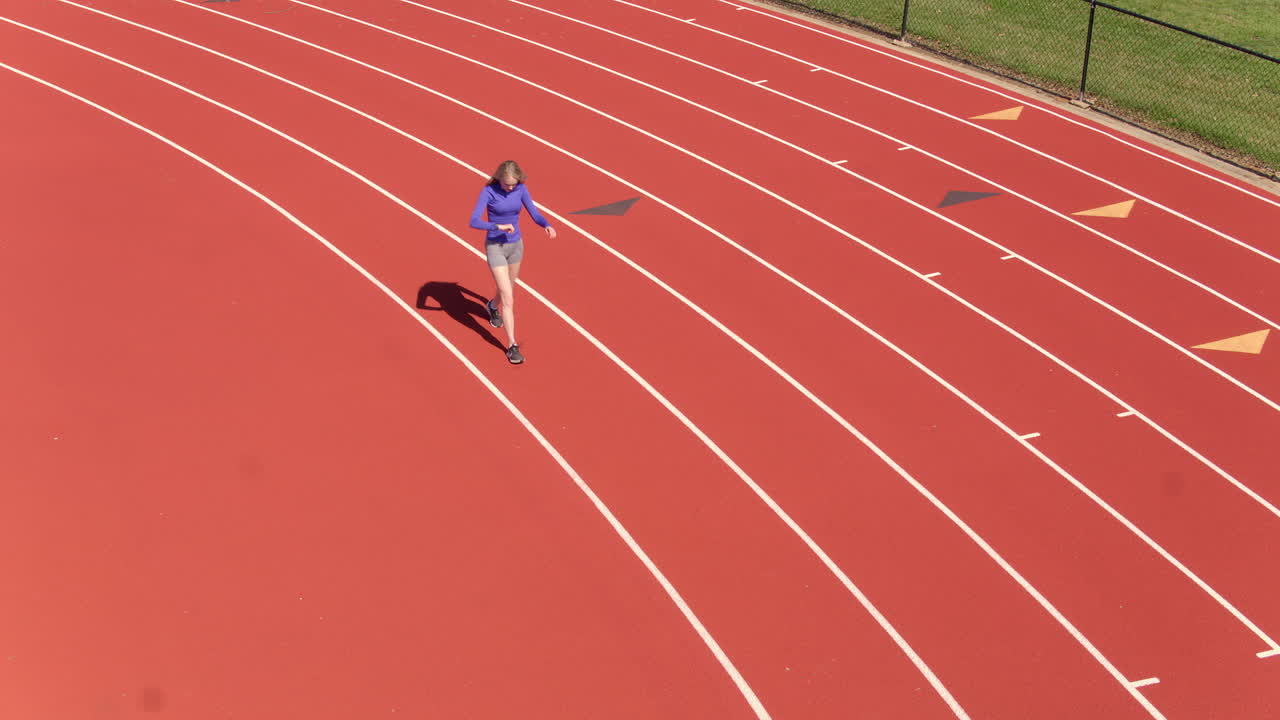 jovencita caminando sobre una pista preparándose para comenzar su carrera