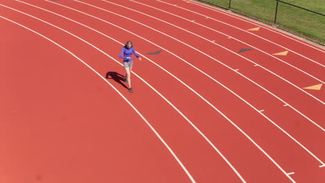 jovencita caminando sobre una pista preparándose para comenzar su carrera