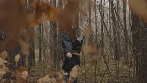 cinematic shot of man walking in the woods, touching tree branch, during autumn