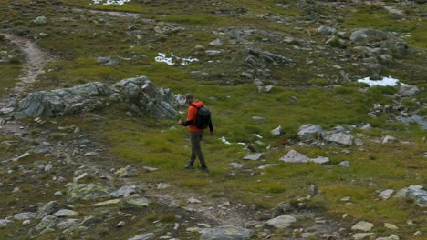 hiker with backpack walking on rocky trail in swiss alps