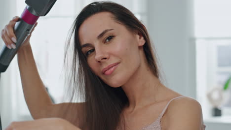 dama morena arreglando el cabello sonriendo en el retrato del baño. chica feliz posando cámara