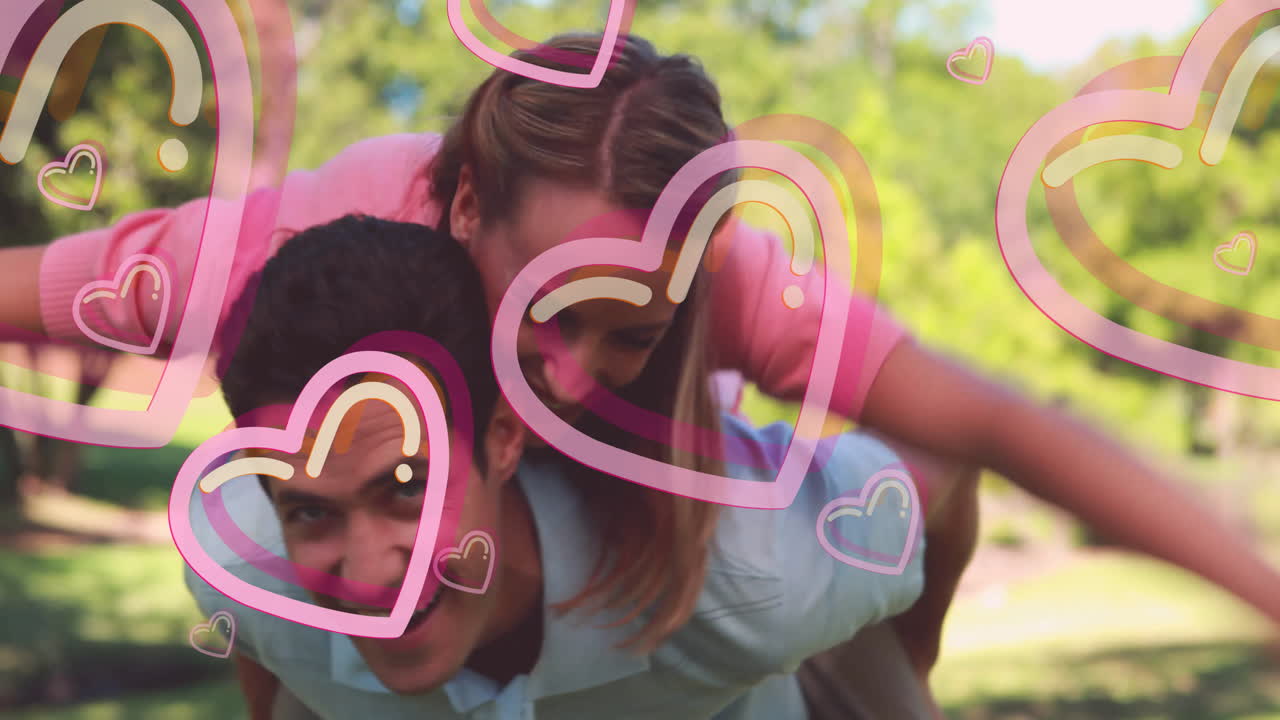 Animated hearts overlaying, couple sharing playful moment outdoors in park setting