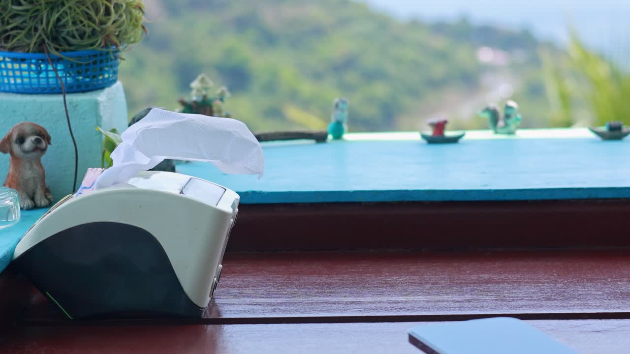 Tissues flutter in the breeze at a Phuket restaurant, with a scenic view in the background