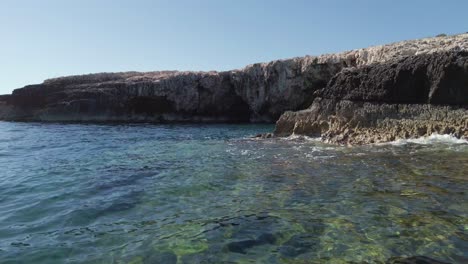 Exploring-the-Mediterranean-sea-coast,-discovering-a-cave-under-the-cliff-behind-the-rocks,-Vis-island,-Adriatic-Sea,-Croatia