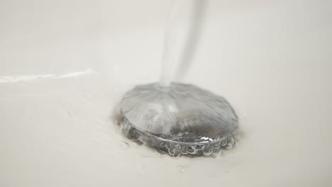 close up of a sink drain with water running into it