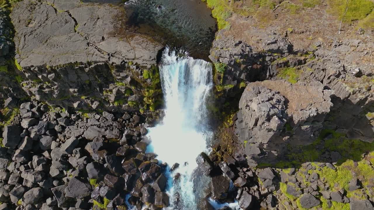 4K cinematic drone footage of Öxarárfoss Waterfall in Iceland, capturing the graceful cascade flowing over rugged volcanic cliffs within Þingvellir National Park. Iceland_17
